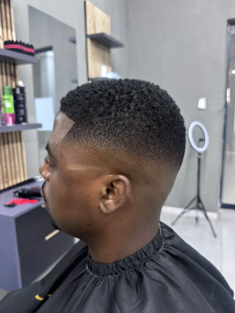 Side profile of a man with a short textured fade haircut in the barbershop