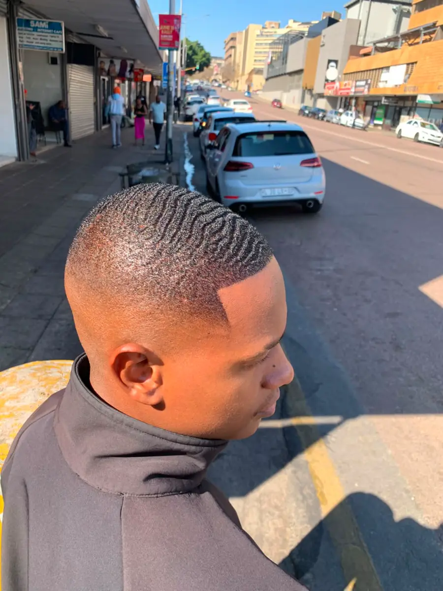 Man with a short waved haircut and sharp fade in a city street
