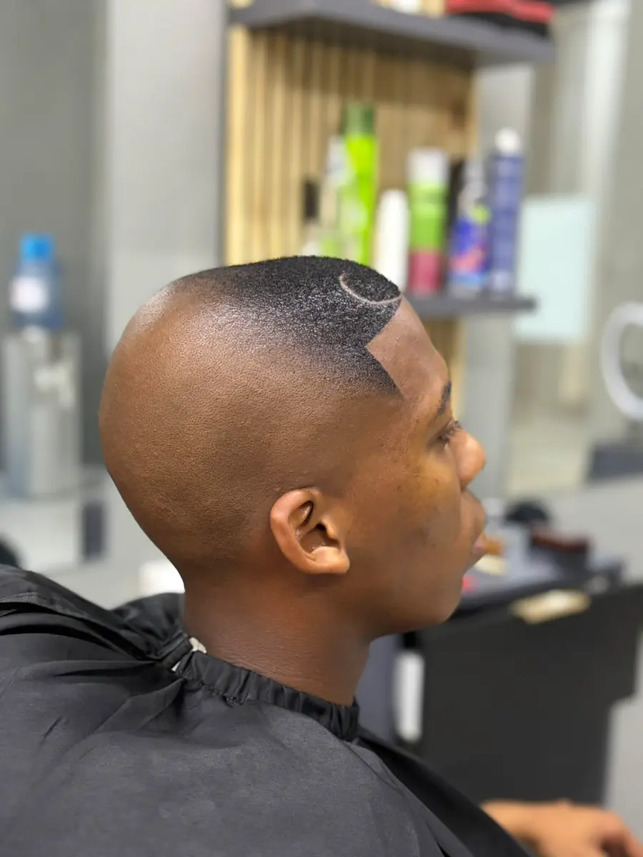 Side-profile portrait showing a short fade haircut with a shaved curved design